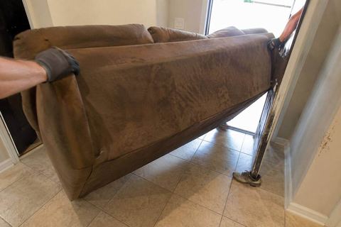 A sofa being carried out through a front doorway