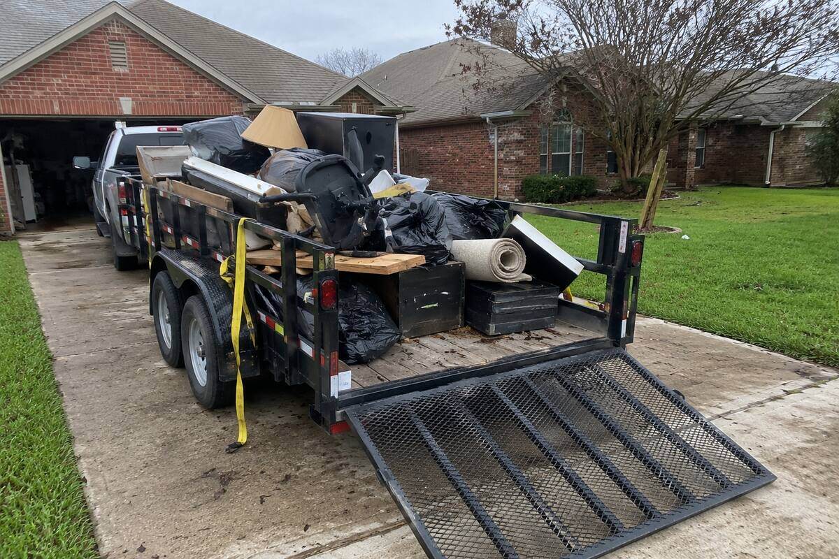 A dump trailer loaded with junk in a driveway